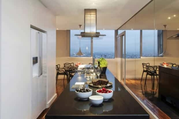 Na cozinha, coifa Smeg e mesa de jantar Saarinen com cadeiras Philippe Starck