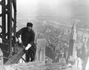 Trabalhadores construindo o Empire State Building, com o Chrysler Building ao fundo