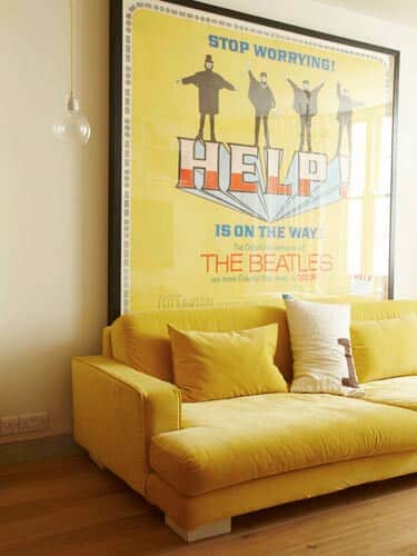 Pôster dos Beatles e um sofá amarelo.