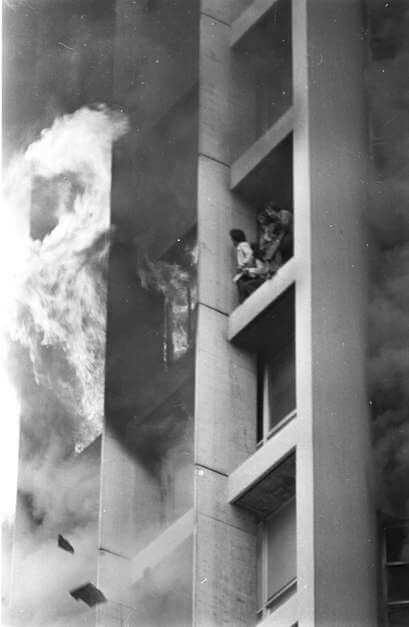 Pessoas presas dentro do Edifício Joelma observam as chamas pelas janelas.