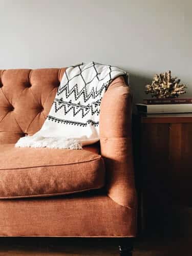 Sofá da sala com uma manta oferecendo um ambiente com conforto térmico e bem aconchegante.
