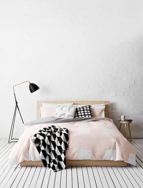 Dormitório minimalista: piso e parede brancos, uma cama e uma luminária ao lado.