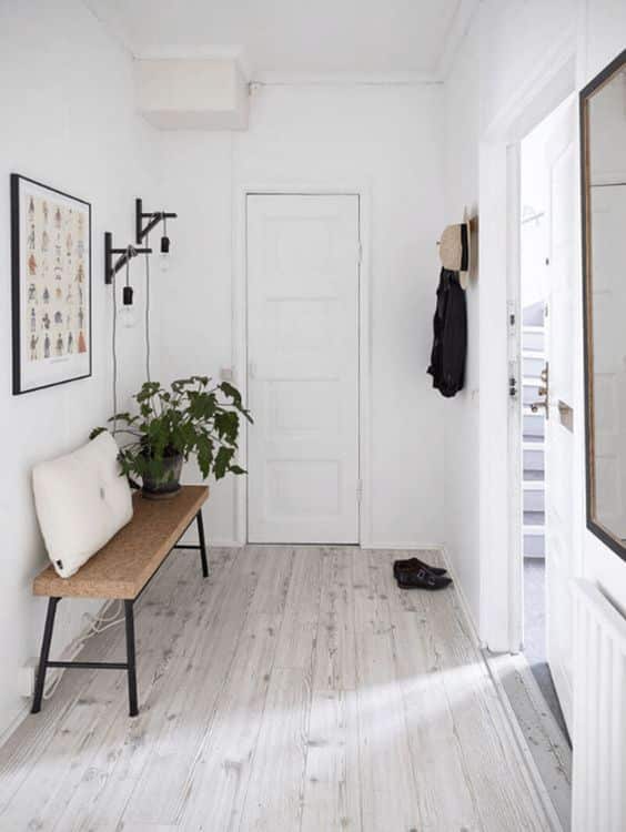 Hall de entrada de uma casa com decoração minimalista, cores claras e poucos móveis.
