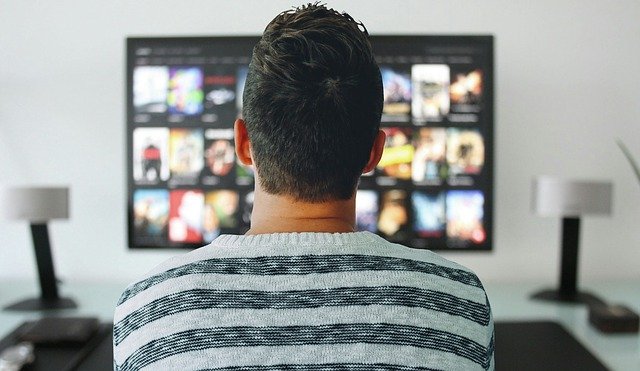 Pessoa assistindo televisão, enquanto escolhe um filme no serviço de streaming.