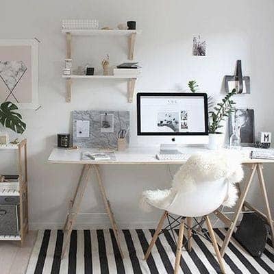 Home office com cores claras e plantas dando um toque decorativo