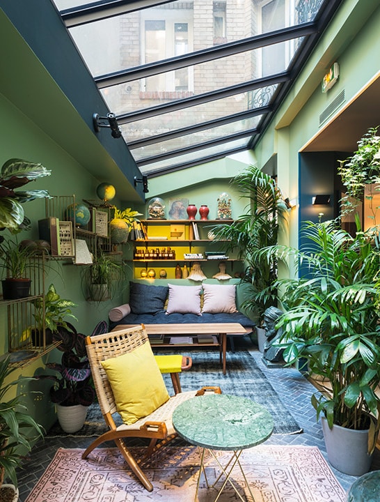 Sala de estar como jardim de inverno, com plantas, iluminaçao zenital e móveis aconchegantes.