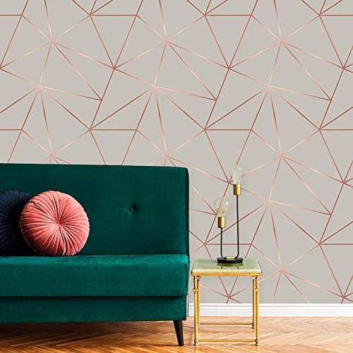 Papel de parede com detalhes geométricos em rosé gold, em uma sala de estar com sofá verde e almofadas rosa e azul marinho.