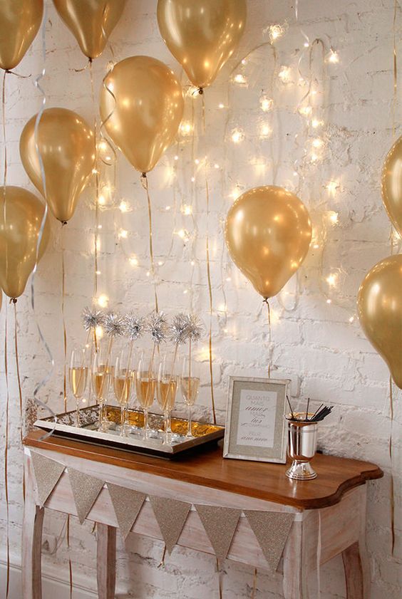 Balões dourados com luzinhas dando um ar de festa na decoração.