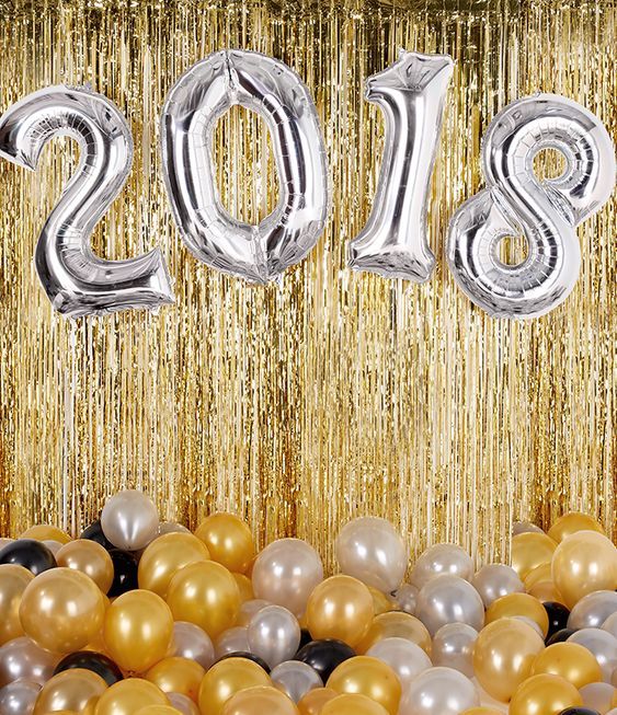 Decoração de ano-novo, com diversas com dourado, prata e preto e diversos elementos como cortina e balões.