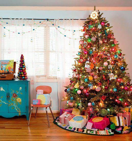 Decoração de árvore de Natal com diversos enfeites muito coloridos, com tons de laranja, turquesa, pink, vermelho, verde, roxo e muito brilho.