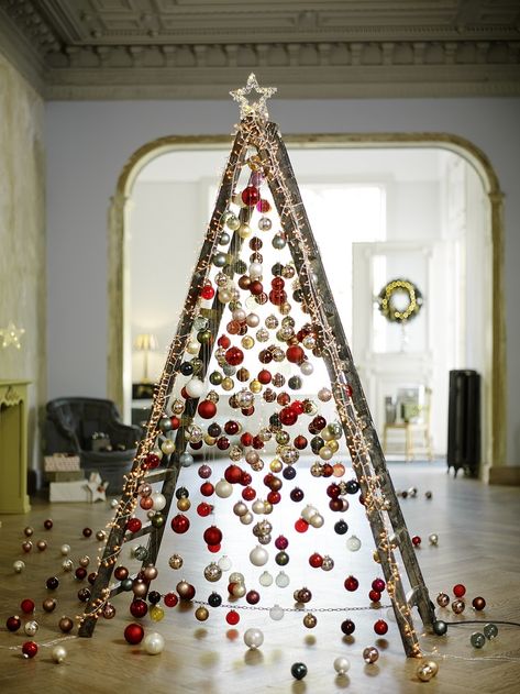 Árvore de Natal feita a partir de uma escada aberta, decorado com bolas de Natal, pisca-piscas e uma estrela brilhante no topo.