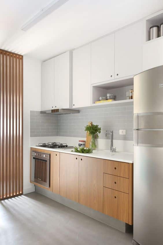 Cozinha planejada linear com armários superiores em branco e os inferiores em madeira em tom intermediário. 