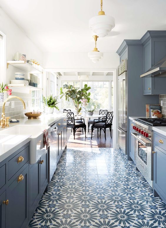 Cozinha planejada paralela com armários em azul e piso com desenho floral em azul e branco.
