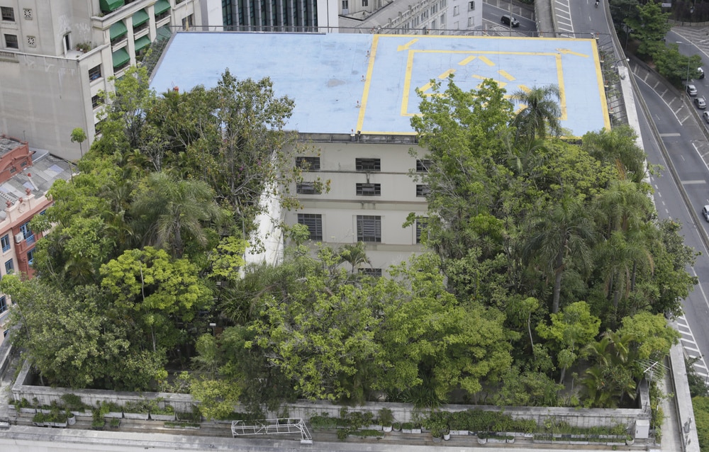 Fotografia aérea do prédio, mostrando o jardim repleto de árvores na cobertura.