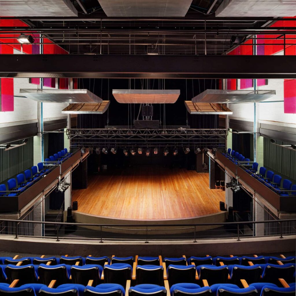 Fotografia do interior do teatro. A vista da arquibancada superior para o palco permite visualizar o palco e também os camarotes laterais.