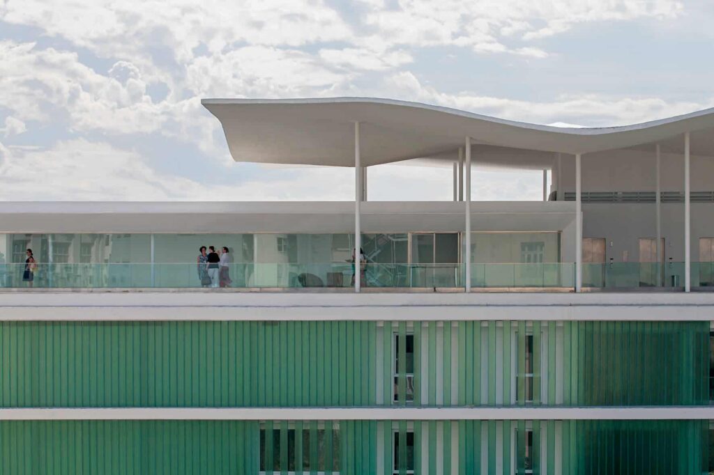Escola do Olhar com terraço que permite vista do entorno, coberto por marquise sinuosa que lembra as ondas do mar.