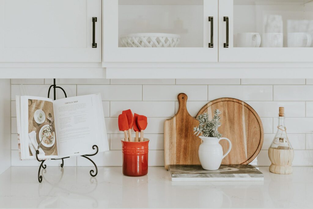 Bancada de cozinha branca com utensílios e livro de receitas.