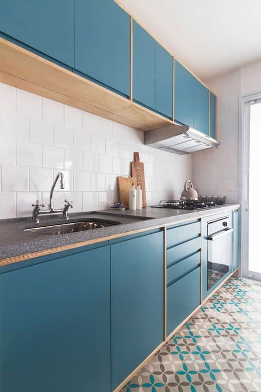 Bancada de cozinha em granito na tonalidade cinza escura e armários azuis com detalhes em madeira.