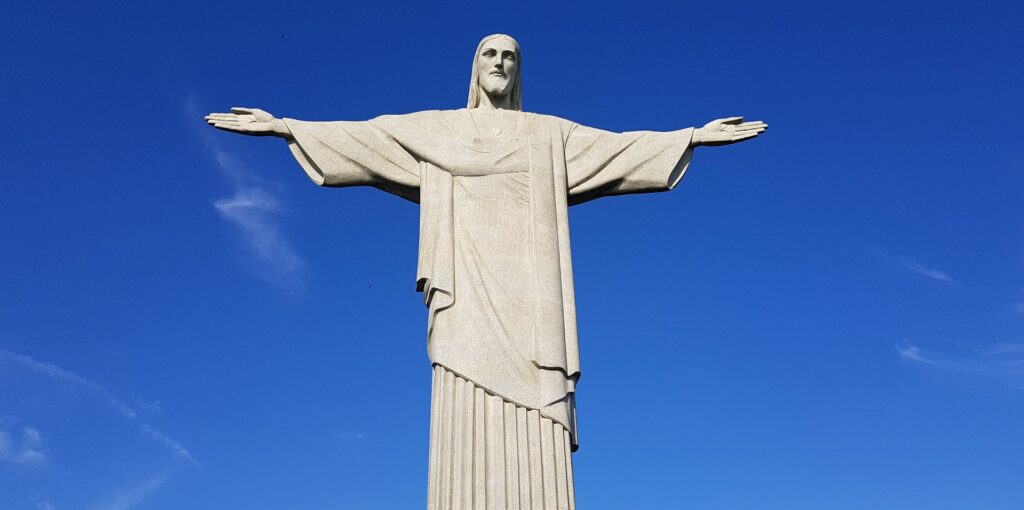 Estátua do Cristo Redentos, de braços abertos em um dia de céu azul e sem nuvens.