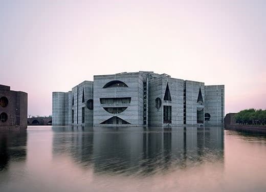 Assembleia Nacional de Bangladesh contornada por um lago que reflete a contrução.
