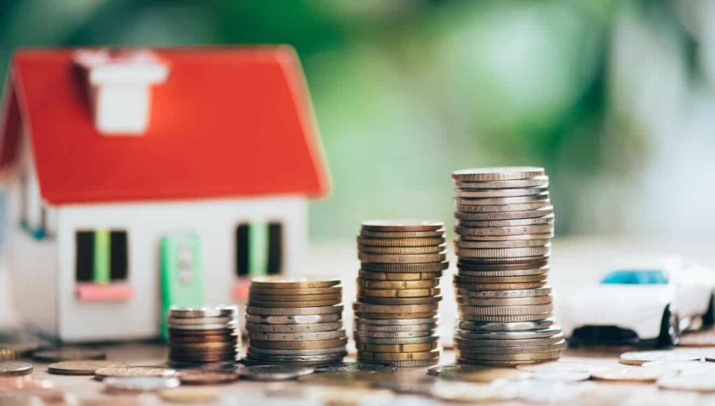 Moedas e casa, representando o ato de investir em imóveis.