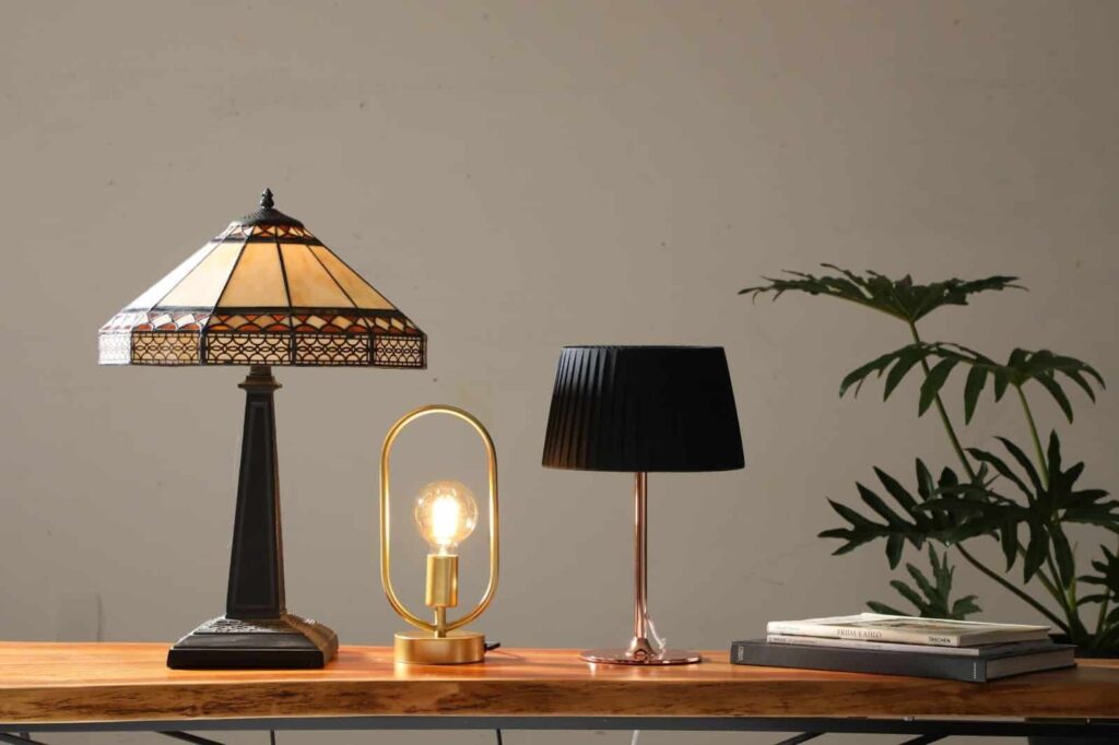 Três luminárias de tamanhos diferentes sobre uma mesa compõem uma decoração clássica e ousada ao mesmo tempo.