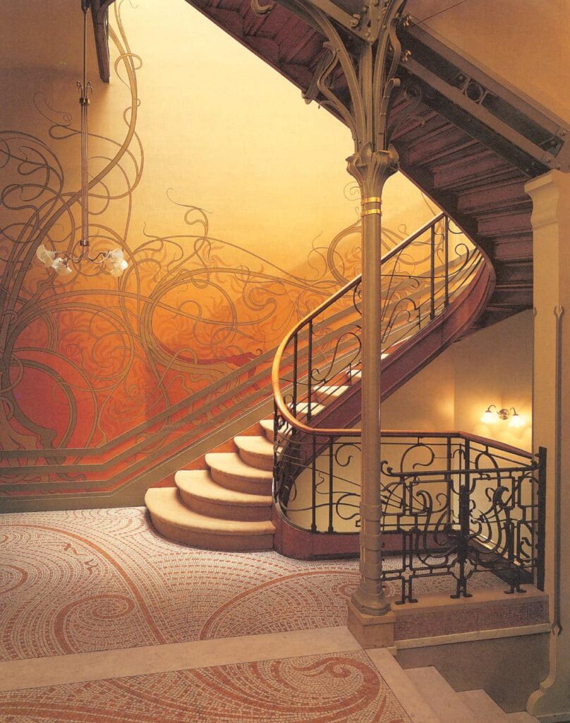 Conversando com o corrimão em estilo Art Nouveau, a paredes do ambiente possuem desenhos fluidos.