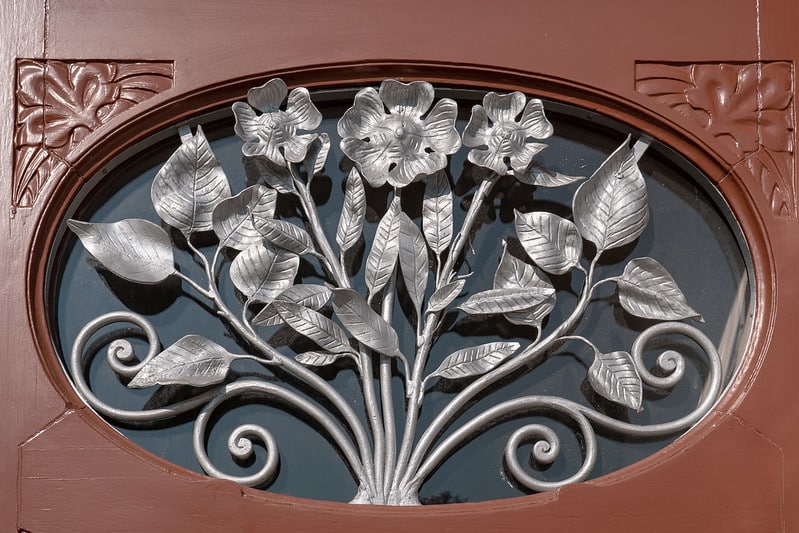 Detalhe de arabesco em metal com entalhes de flores e folhas.