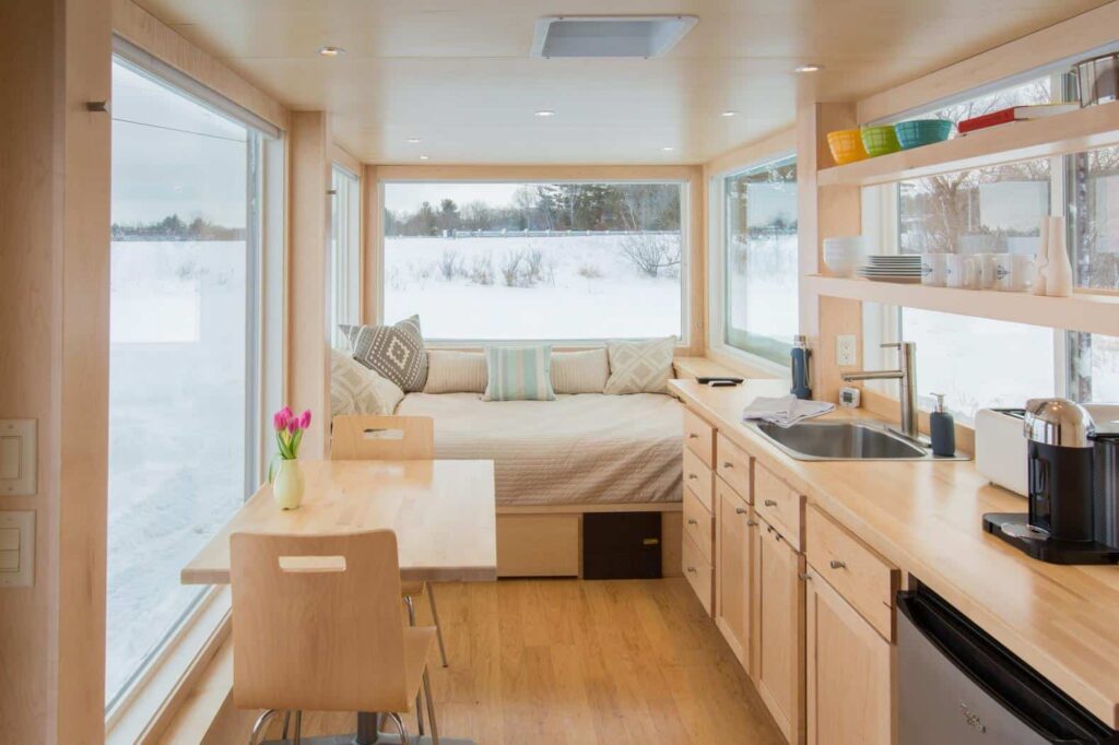 Interior de pequena residência integrando cozinha, jantar e espaço de estar/descanso.