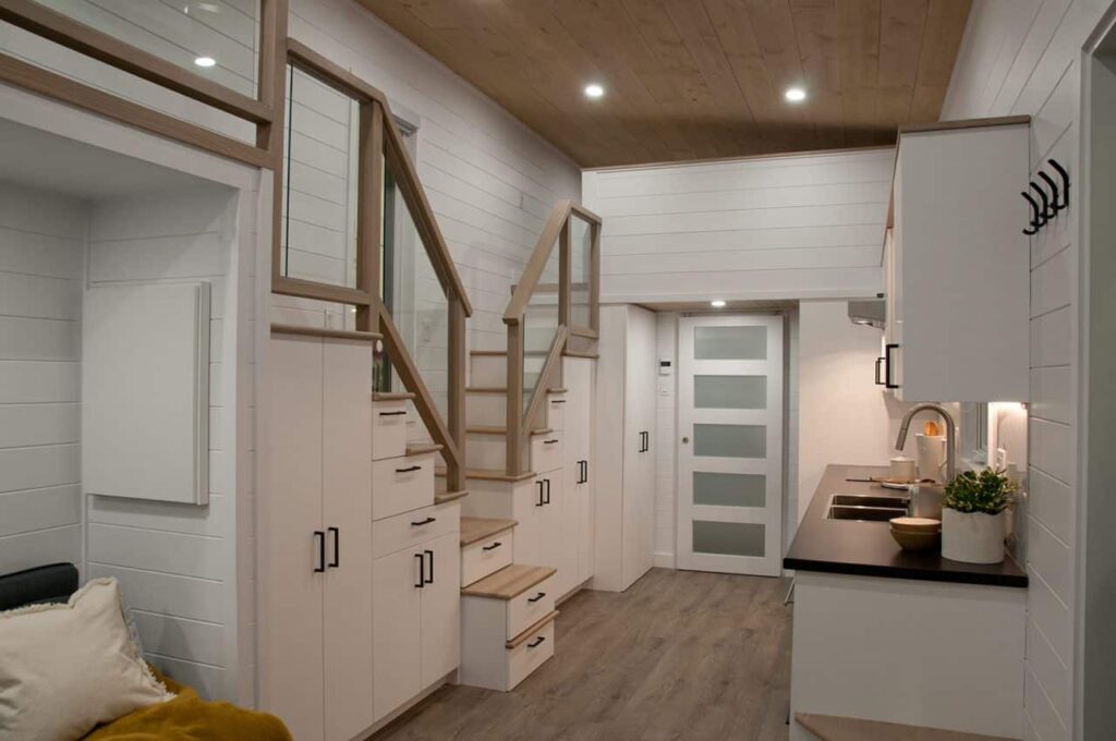 Interior de micro casa, com armários e gavetas aproveitando os degraus das escadas.