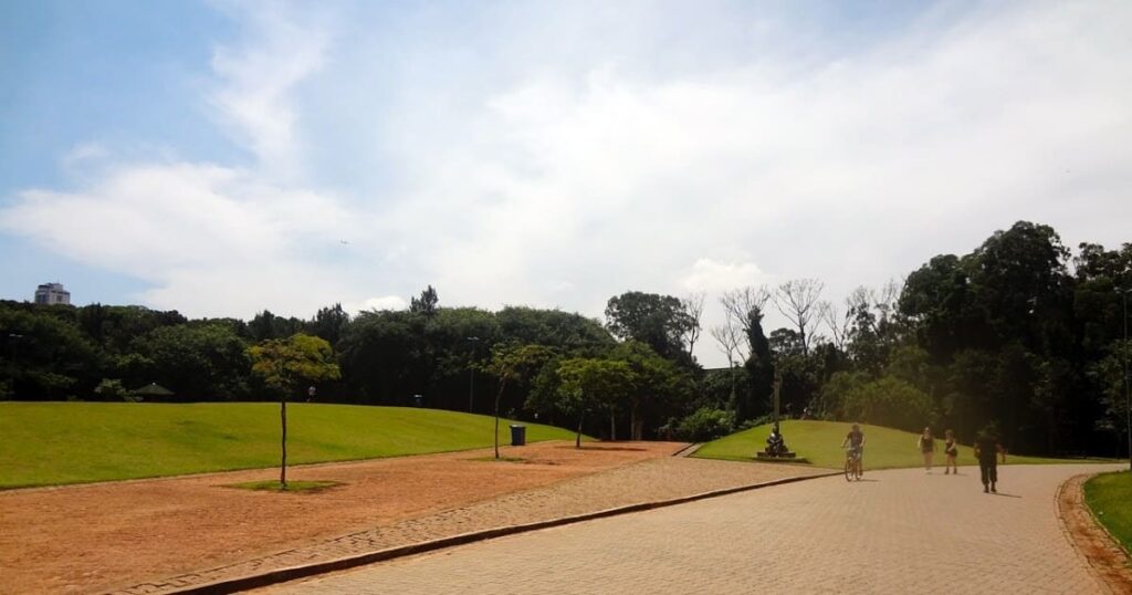 Ampla área verde do Parque da Juventude, onde pessoas caminham e andam de bicicleta.