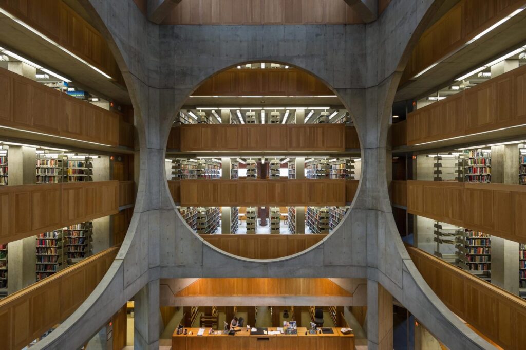 Estrutura em concreto contrastando com o mobiliário amadeirado da biblioteca.