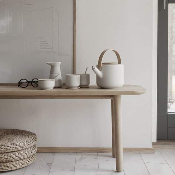 Mesa pequena em madeira com alguns objetos em cima na coloração branca.