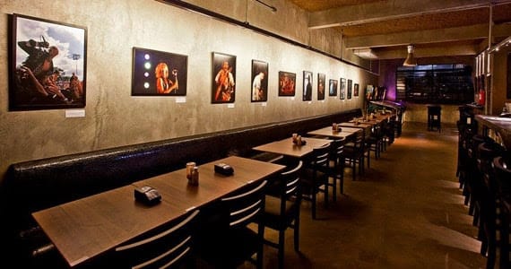 O restaurante Rock 'n Roll Burger conta com estofado, mesas e cadeiras de madeira e uma parede repleta de quadros com bandas e artistas do rock.