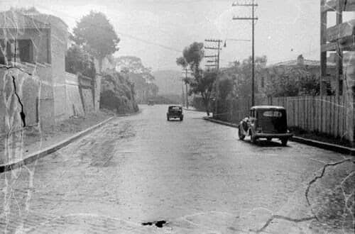 Rua Augusta antigamente: rua pacata com dois carros, rodeada por poucas casas e alguma vegetação.