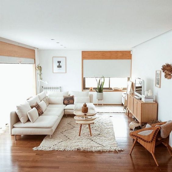 Sala de estar com um sofá branco, tapete de pelos branco e objetos em madeira.