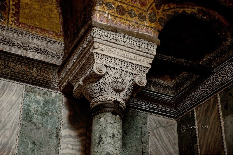 Coluna em tons de verde marmorizado e com detalhes superiores entalhados.
