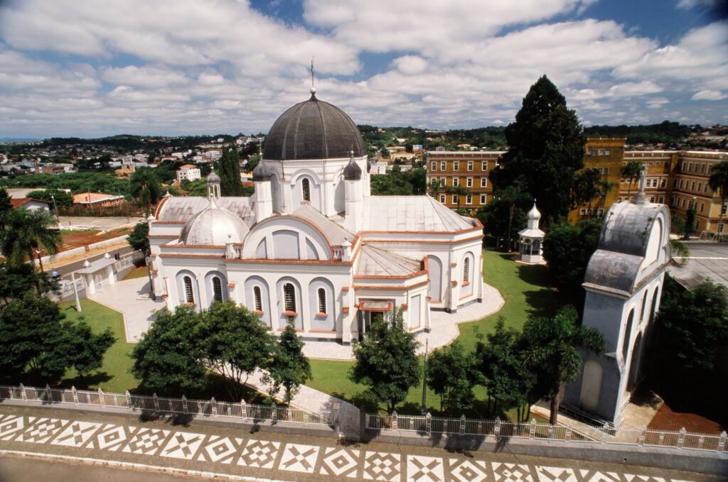 Vista aérea da igreja, coroada por uma cúpula em tons de cinza que se destaca da construção.