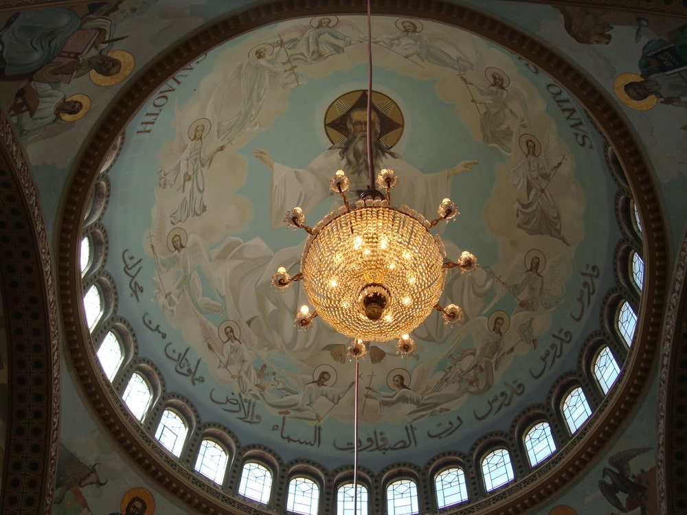 Vista interna da cúpula central inspirada na arquitetura bizantina, com fundo azul e lustre pendente.