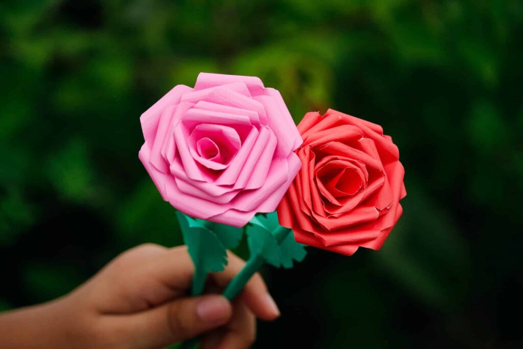 Passo a passo de flores de papel: uma pessoa segura duas rosas, uma rosa e uma vermelha.