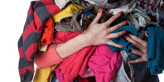 Mulher segurando diversas roupas de cores diferentes.