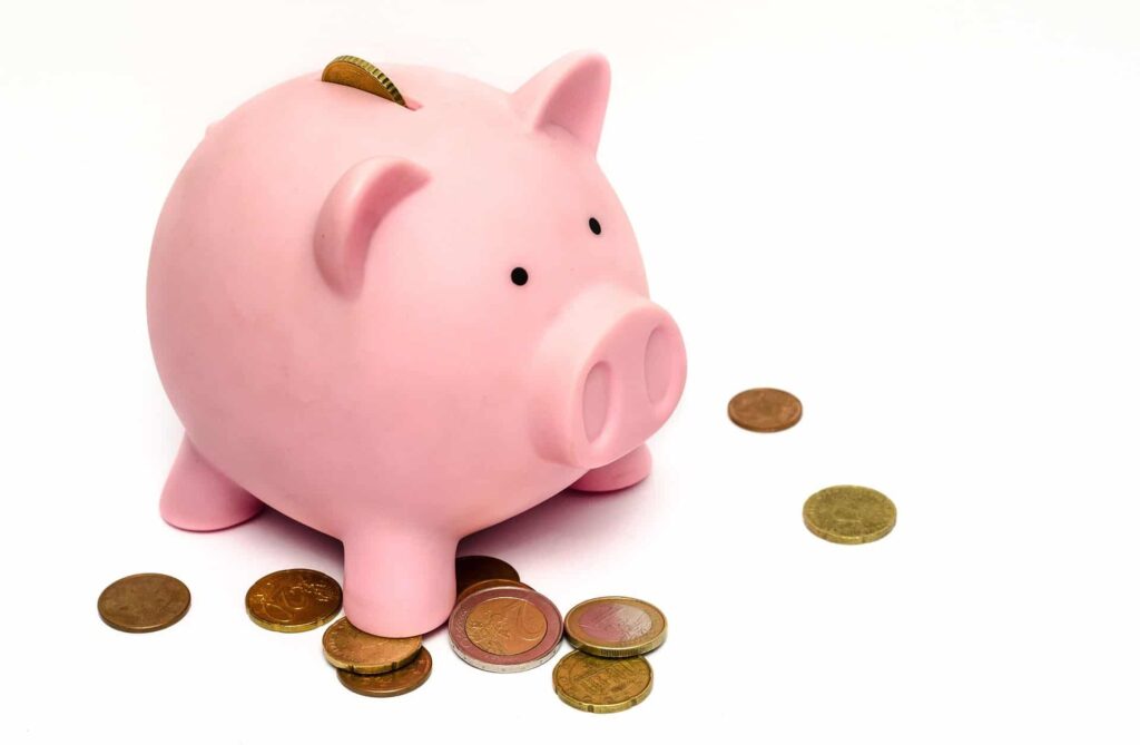 Cofre de porquinho rosa, com algumas moedas no chão, representando a economia de optar por um imóvel alugado. 