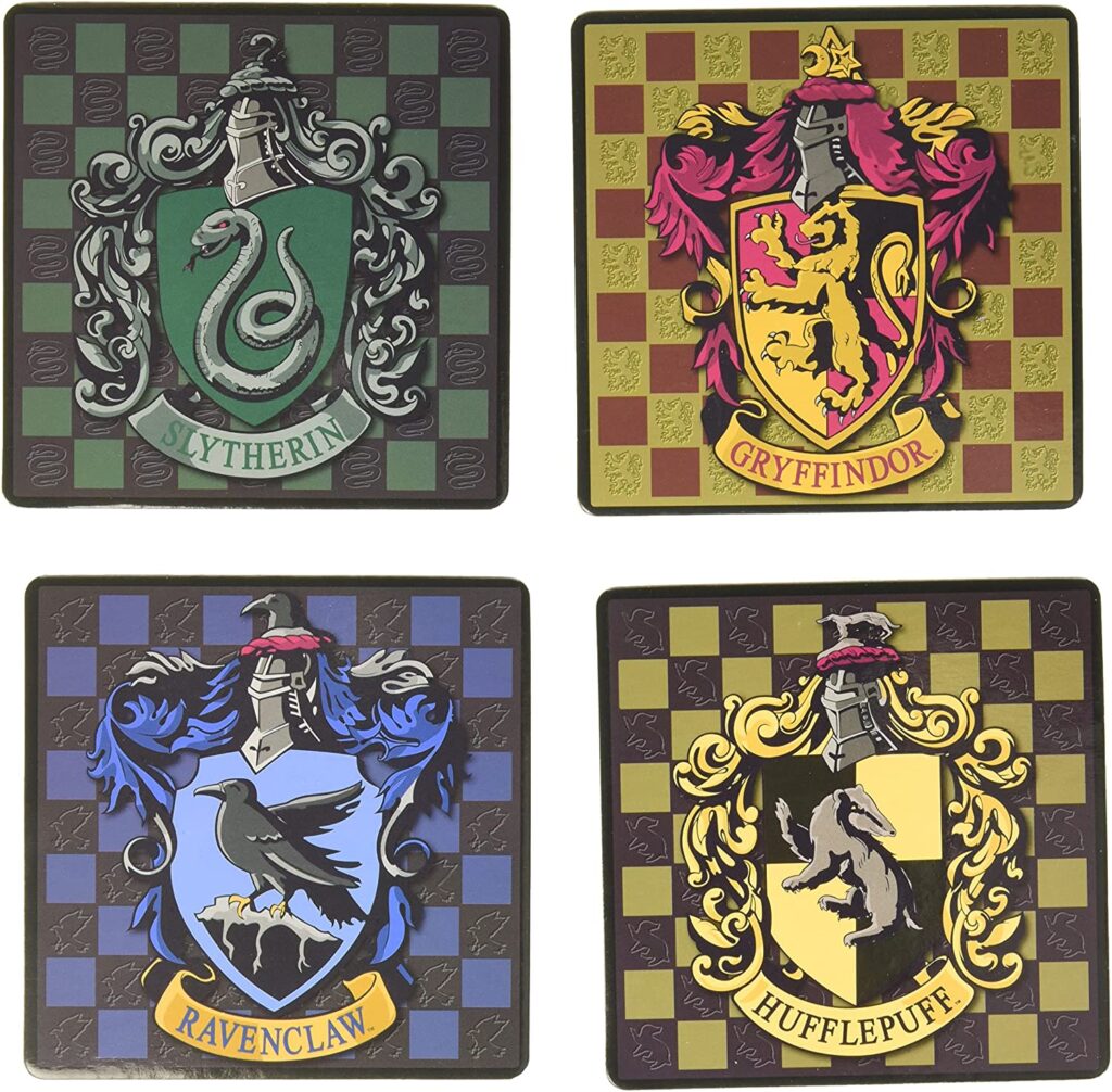 Quatro porta copos do Harry Potter, todos quadriculados e cada um com o brasão de suas respectivas casas: Slytherin, Gryffindor, Ravenclaw e Hufflepuff.