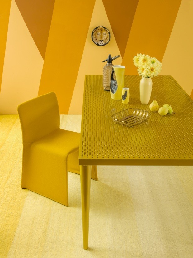 Espaço da mesa de jantar decorada com tons de amarelo-escuro e amarelo-claro, tanto nas paredes, quanto nos móveis e nos objetos decorativos. 